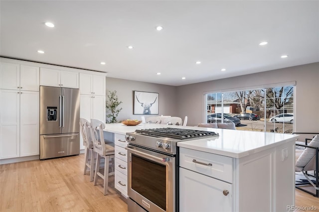 5404 W Rowland Pl, Littleton, CO 80128 - kitchen with stainless steel appliances, recessed lighting, white cabinets, light wood finished floors, and a kitchen island