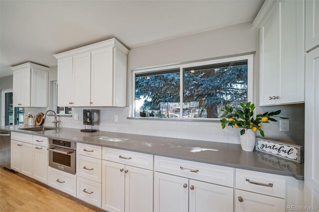 5404 W Rowland Pl, Littleton, CO 80128 - kitchen with stainless steel appliances, plenty of natural light, white cabinets, and light wood finished floors
