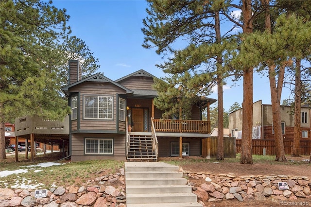 view of front of house featuring stairway, a chimney, fence, a deck, and covered porch