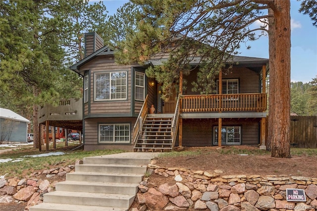 rustic home featuring stairway, a chimney, fence, and a wooden deck
