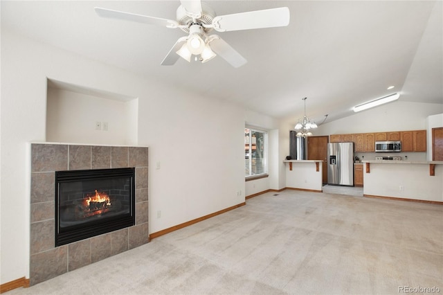 unfurnished living room featuring vaulted ceiling, a chandelier, a tiled fireplace, light carpet, and baseboards