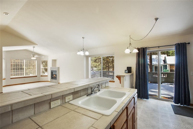 kitchen featuring a sink, healthy amount of natural light, a chandelier, tile counters, and vaulted ceiling