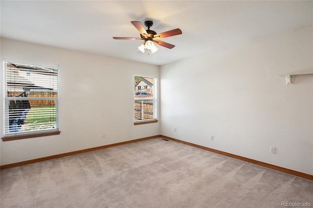 spare room featuring light carpet, baseboards, and ceiling fan