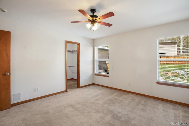 spare room with light carpet, ceiling fan, and baseboards