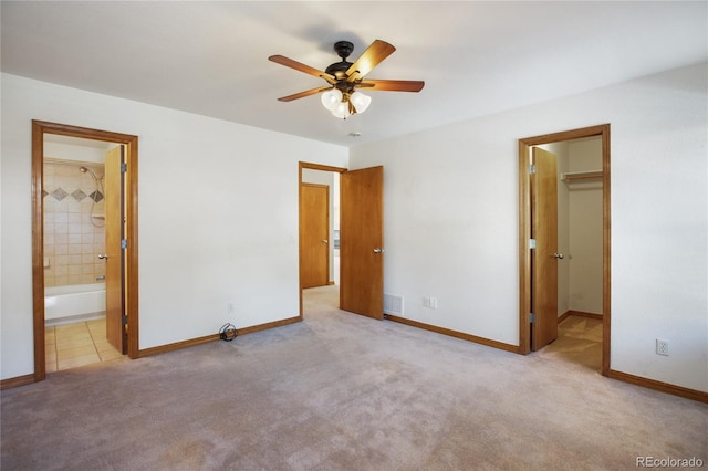 unfurnished bedroom with a spacious closet, carpet floors, baseboards, and ensuite bath