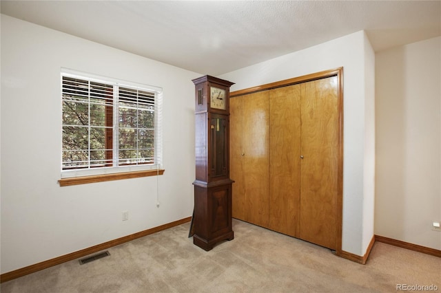 unfurnished bedroom featuring light carpet, baseboards, and a closet