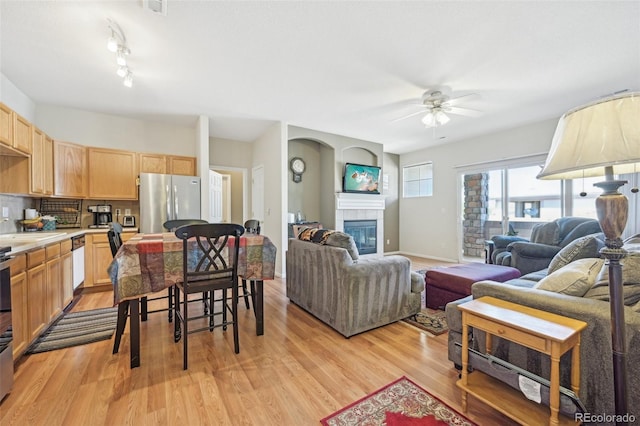 living room with ceiling fan, track lighting, light hardwood / wood-style flooring, and a tile fireplace