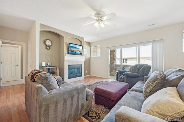 living room with a fireplace, light wood-type flooring, and ceiling fan