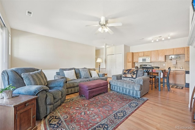 living room featuring ceiling fan, rail lighting, and light hardwood / wood-style floors