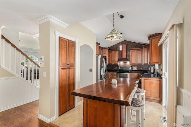 5326 E Hamilton Ave, Castle Rock, CO 80104 - kitchen with stainless steel appliances, wall chimney range hood, lofted ceiling, brown cabinets, and tasteful backsplash