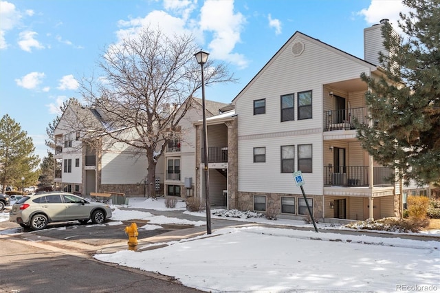 snow covered property featuring uncovered parking