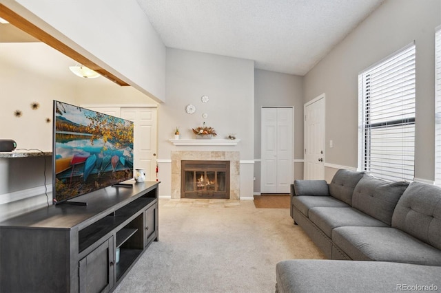 living room with lofted ceiling, a textured ceiling, a tile fireplace, light colored carpet, and baseboards