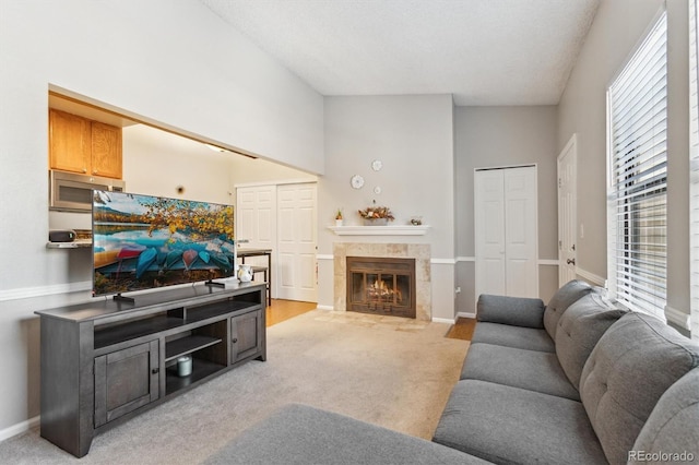 living room featuring light carpet, a fireplace, and baseboards