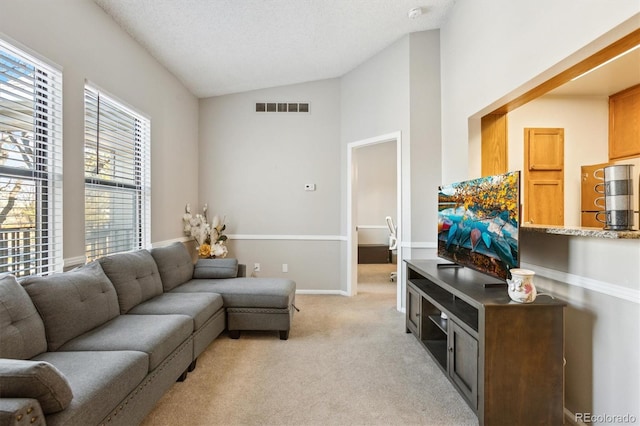 living area with lofted ceiling, a textured ceiling, light colored carpet, visible vents, and baseboards