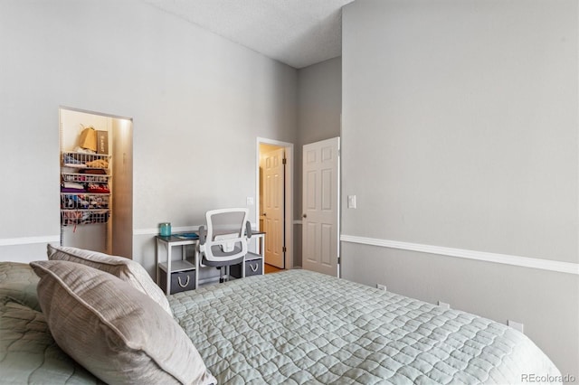 bedroom with a towering ceiling, a walk in closet, and a textured ceiling