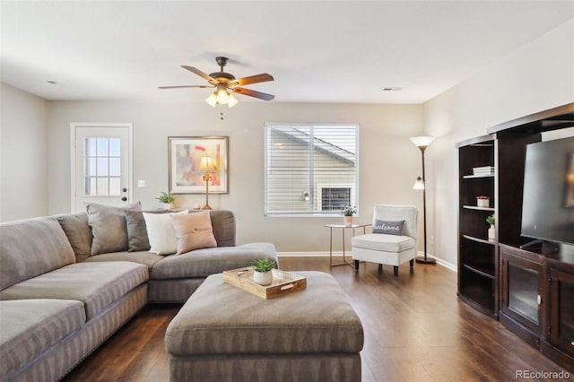 living area featuring baseboards, ceiling fan, dark wood-style flooring, and a healthy amount of sunlight