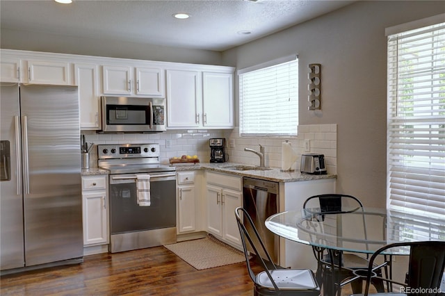 kitchen with stainless steel appliances, dark wood finished floors, a sink, and white cabinetry