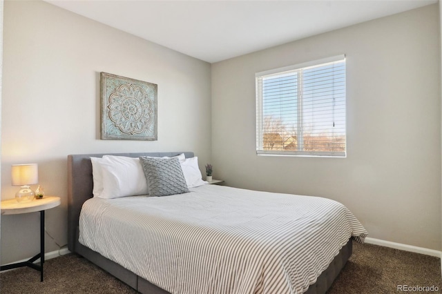 bedroom with dark colored carpet and baseboards