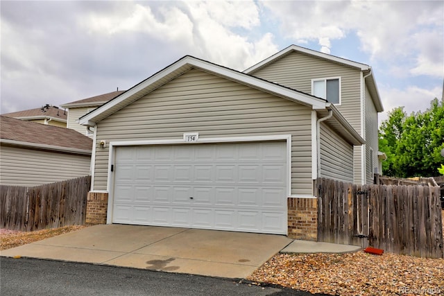 traditional-style home featuring an attached garage, fence, concrete driveway, and brick siding