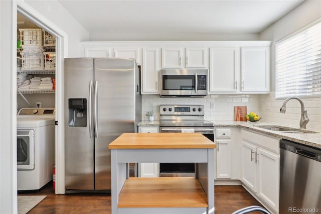 kitchen featuring white cabinets, appliances with stainless steel finishes, washer / clothes dryer, wooden counters, and a sink