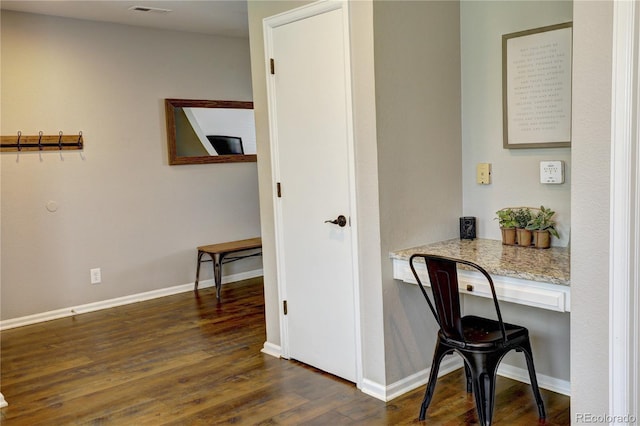 office area with built in desk, dark wood finished floors, visible vents, and baseboards