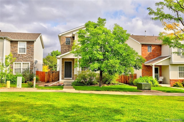 view of front of house featuring a front yard, brick siding, and fence