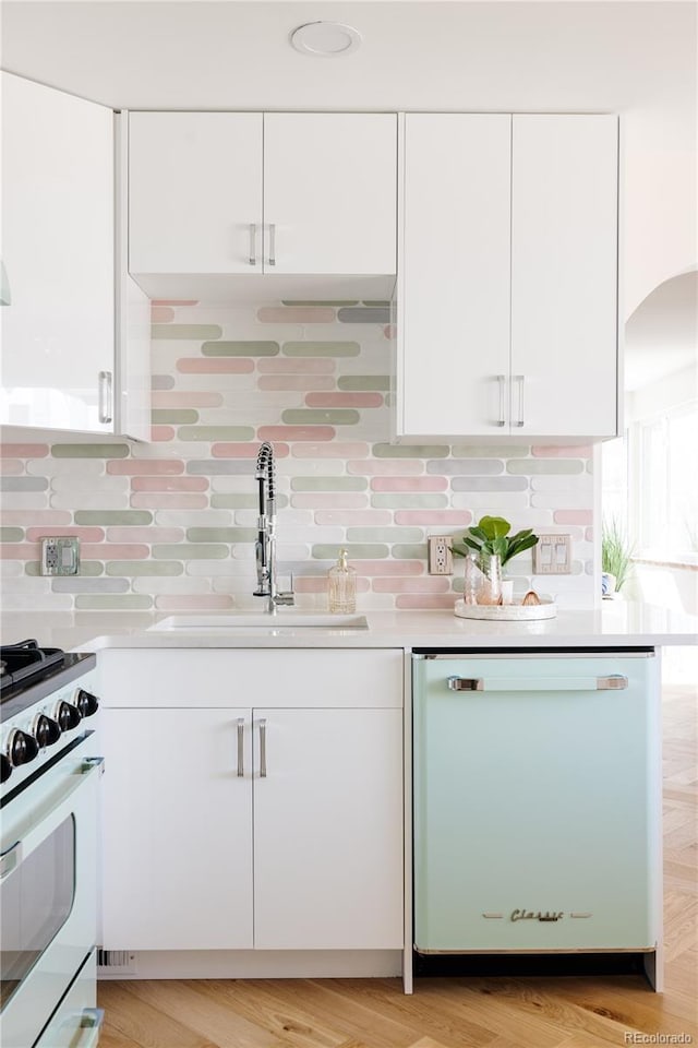 kitchen featuring white cabinetry, white appliances, light countertops, and a sink