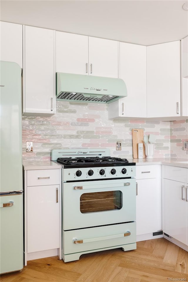 kitchen featuring under cabinet range hood, white appliances, white cabinets, and light countertops