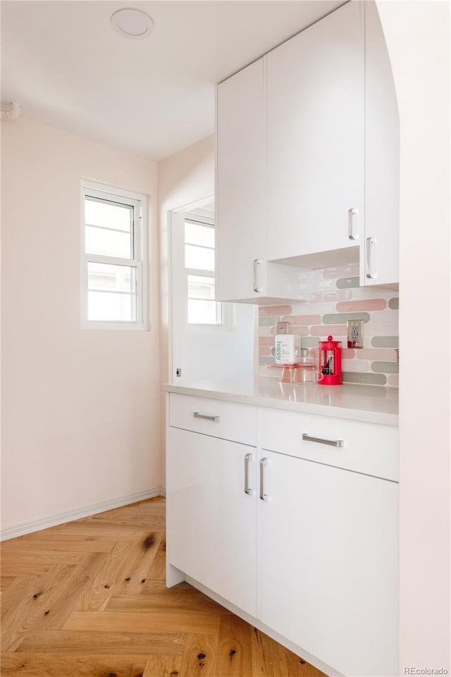 kitchen featuring light countertops, white cabinets, baseboards, and tasteful backsplash