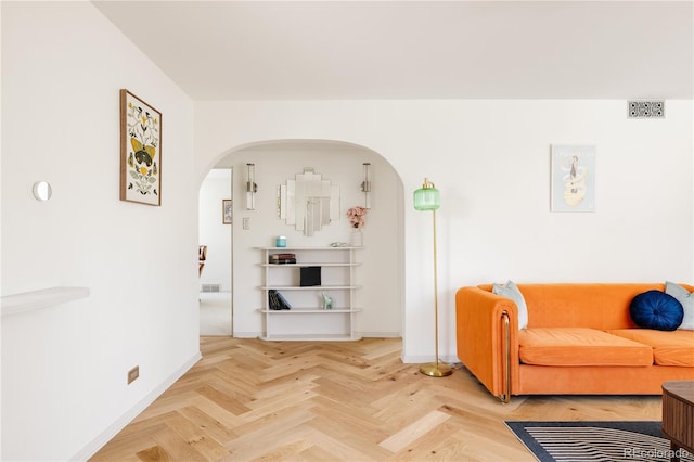 living area with baseboards and arched walkways