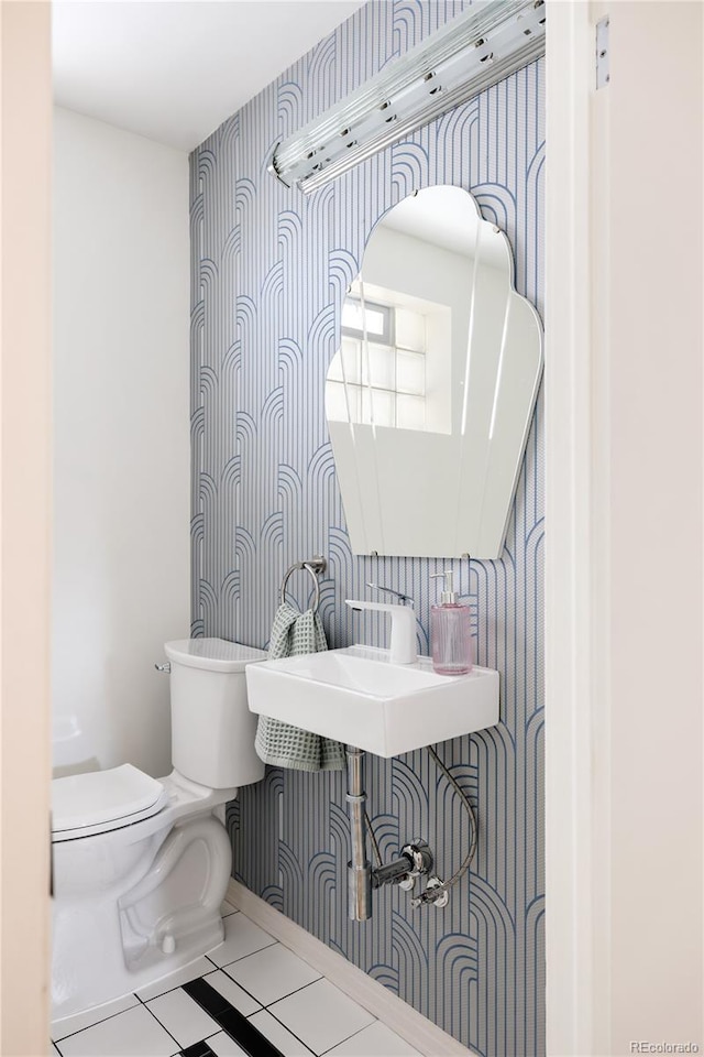 half bath featuring toilet, tile patterned flooring, and wallpapered walls