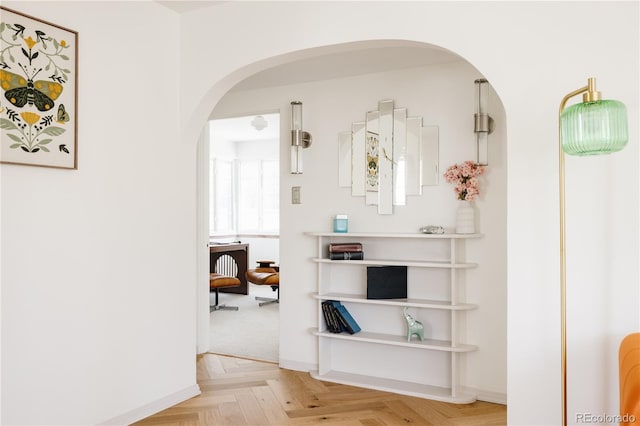 corridor featuring baseboards and arched walkways