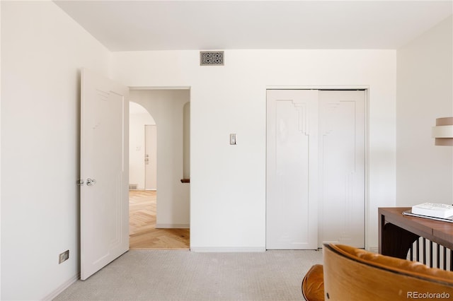 bedroom featuring visible vents, baseboards, a closet, light carpet, and arched walkways