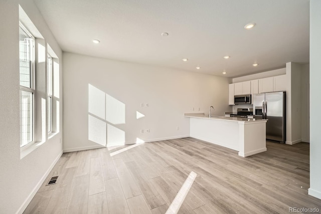 kitchen with white cabinetry, appliances with stainless steel finishes, plenty of natural light, and kitchen peninsula