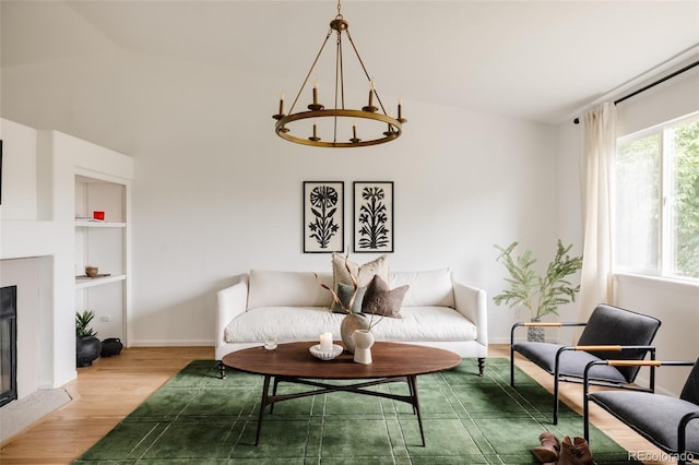 9756 Autumnwood Pl, Highlands Ranch, CO 80129 - living area featuring wood finished floors, vaulted ceiling, a glass covered fireplace, a chandelier, and built in shelves