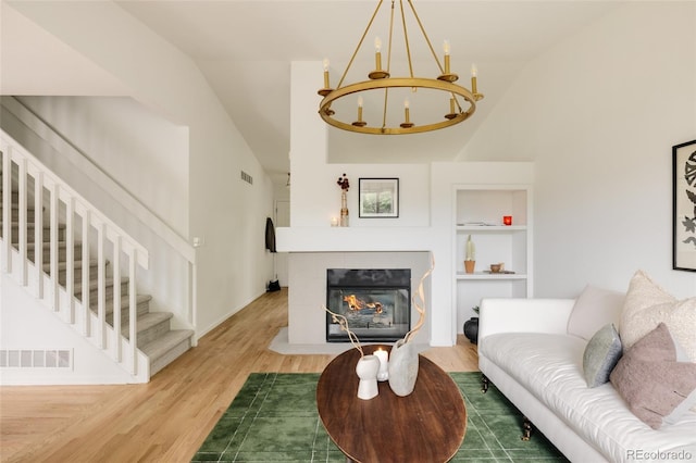 9756 Autumnwood Pl, Highlands Ranch, CO 80129 - living area featuring lofted ceiling, stairs, wood finished floors, a chandelier, and a tiled fireplace