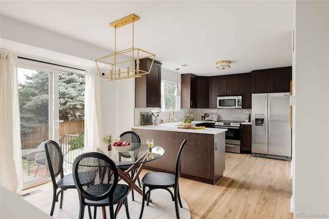 9756 Autumnwood Pl, Highlands Ranch, CO 80129 - kitchen featuring stainless steel appliances, a chandelier, dark brown cabinets, light countertops, and light wood-type flooring