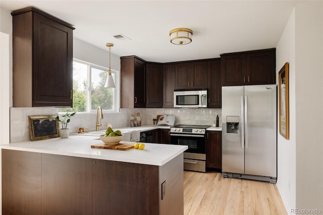 9756 Autumnwood Pl, Highlands Ranch, CO 80129 - kitchen with stainless steel appliances, a peninsula, dark brown cabinets, light countertops, and light wood finished floors