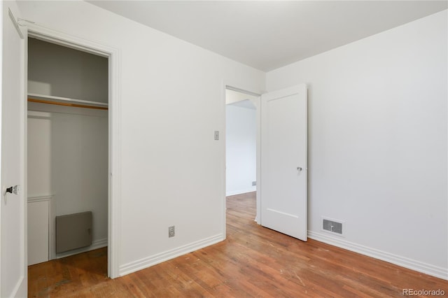 unfurnished bedroom featuring wood-type flooring and a closet