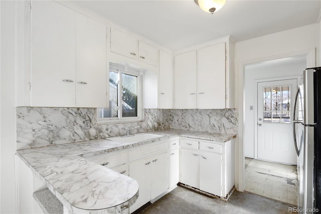 kitchen featuring white cabinets, stainless steel fridge, tasteful backsplash, and sink