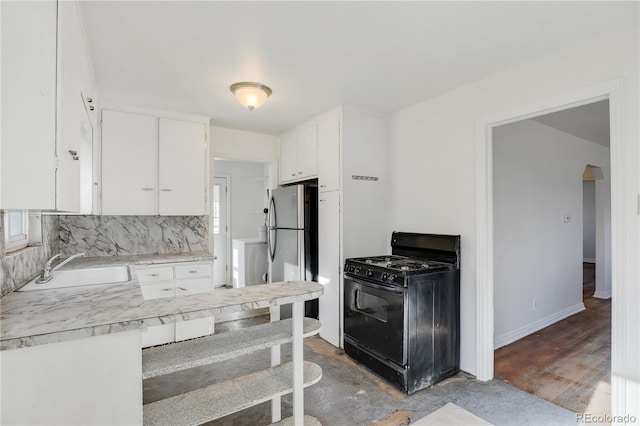 kitchen featuring gas stove, stainless steel refrigerator, white cabinetry, sink, and backsplash