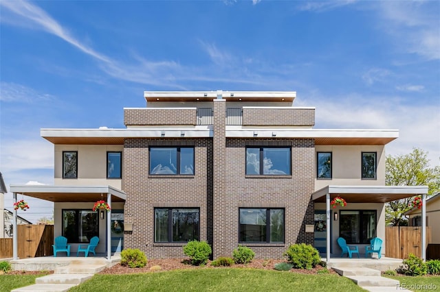 back of house featuring fence, brick siding, and a patio