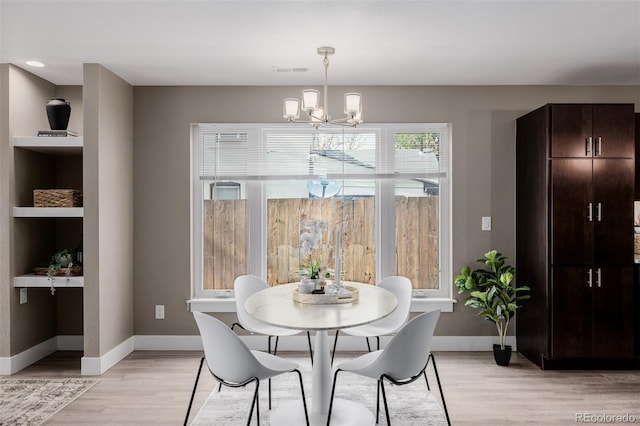 dining room featuring a chandelier, light wood-type flooring, and baseboards