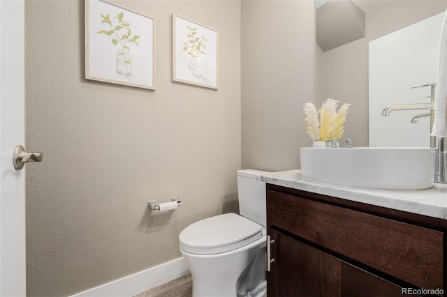 half bath featuring vanity, toilet, and baseboards