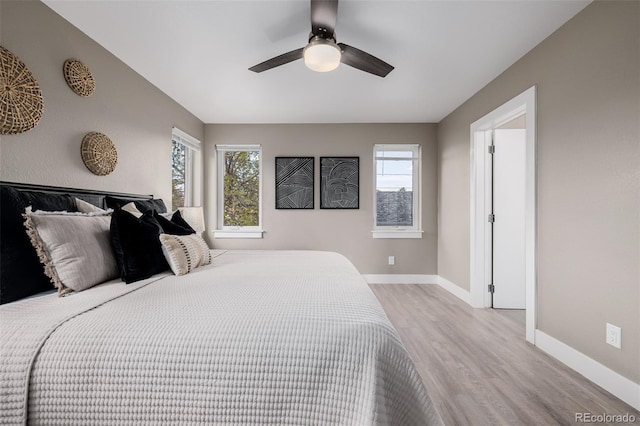 bedroom featuring light wood-style flooring, multiple windows, baseboards, and a ceiling fan