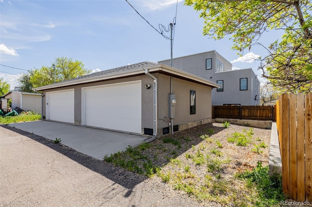 view of side of property featuring a garage, fence, and stucco siding