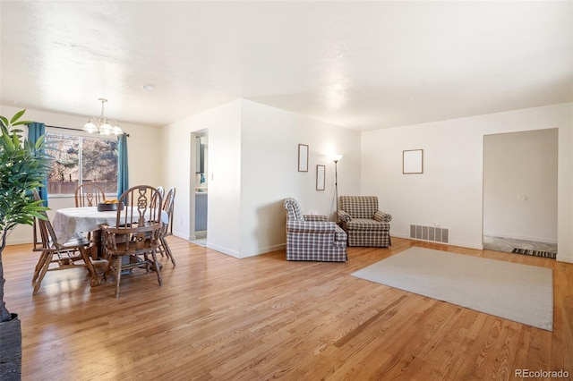 dining area with a chandelier, light wood-style flooring, visible vents, and baseboards