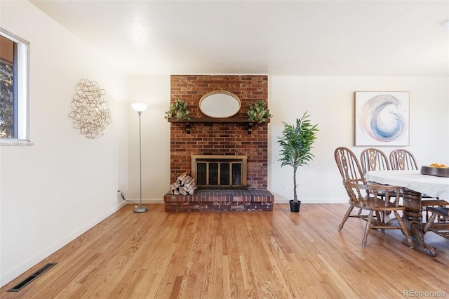 dining area with a fireplace, wood finished floors, visible vents, and baseboards