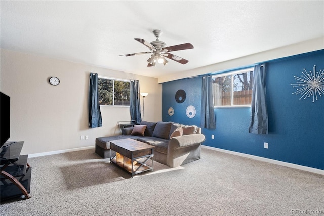 carpeted living area with ceiling fan and baseboards