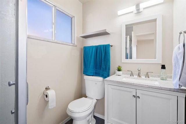 bathroom with baseboards, vanity, and toilet